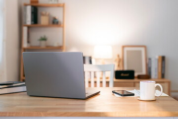 Close up view of simple workspace with laptop, notebooks on wooden desk, home office, work from home.