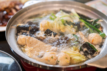closeup sukiyaki or hot pot to boiling water or suki soup bubbles with delicious meatball vegetable and seaweed wrapped meatballs for healthy dinner or lunch at japanese food restaurant in thailand