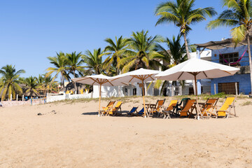 Panorama of the beach in Jalisco, Mexico with lounge chairs on the beach outside hotels for people to rest