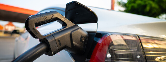 EV charger handle plugged in connect to electric car outdoor station