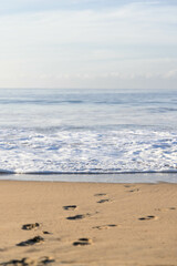Panorama of beach in Jalisco, Mexico with breaking waves arriving very slowly and in the sand you can see footprints of a person walking on the sand