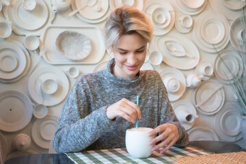 young beautiful woman sitting in a cafe and drinking coffee