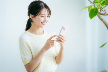部屋でスマホを操作する女性
