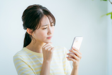 部屋でスマホを操作する女性