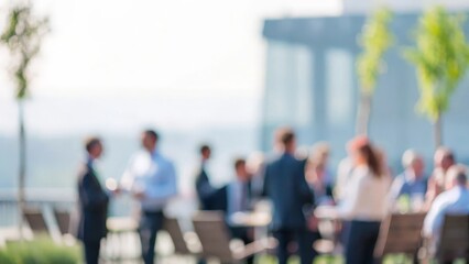 A blurred image of professionals networking in an outdoor setting, such as a garden or patio.

