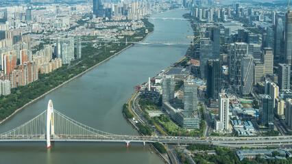 Obraz premium Panorama of Guangzhou city. View from the Canton TV tower. ZhuJiang River and bridges over the riverbed. Green vegetation on the shores. Tall multi-storey towers, skyscrapers. China