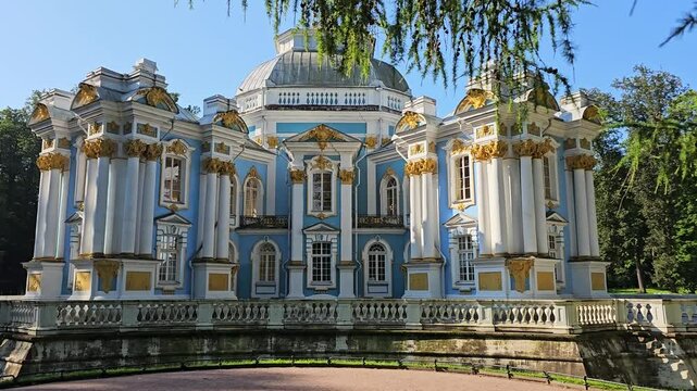 The Hermitage Pavilion in Catherine Park, Tsarskoye Selo, near Saint Petersburg, Russia. The ornate baroque architecture features blue and white walls with gold detailing, surrounded by greenery