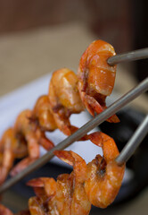 Perfectly grilled Brazilian shrimp skewer with golden, crispy texture on a metal trident.