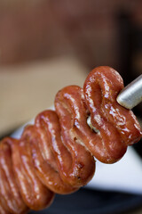 Close-up of a Brazilian-style white sausage skewer with intricate details, smoky and golden crust.