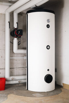 Water heater in boiler room of residential building. Hot water heating system in service room or basement. Smart circulator pump with return and supply pipes. Lucerne, Switzerland. Selective focus.
