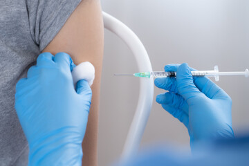 Hand of young woman nurse, doctor giving syringe vaccine, inject shot to Asian arm's patient. Vaccination, immunization or disease prevention against flu or virus pandemic concept