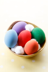 Happy Easter eggs in a bowl on dot yellow color background.