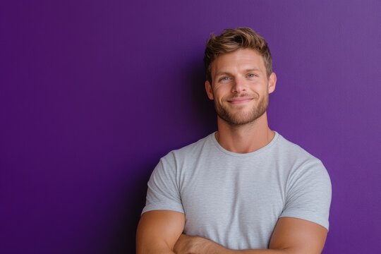 Smiling caucasian man with short blonde hair wearing light grey t-shirt against vibrant purple background in casual portrait
