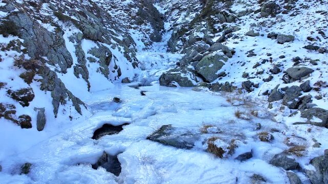 Aerial view of a frozen waterfall creek in the European Alps