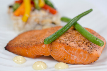 Healthy grilled salmon with aioli and steamed green beans, presented in an upscale restaurant setting.