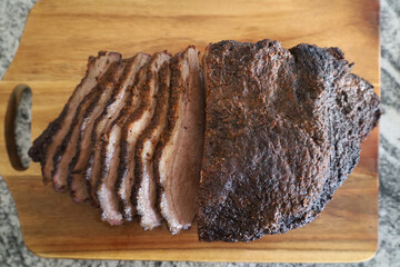 Sliced smoked brisket with bark on a wooden cutting board