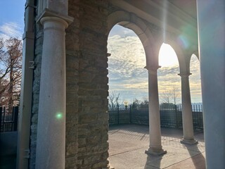 Sunlight streaming through stone arches, columns with trees