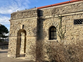 Fototapeta premium Historic stone building with ivy, arched doorway, window