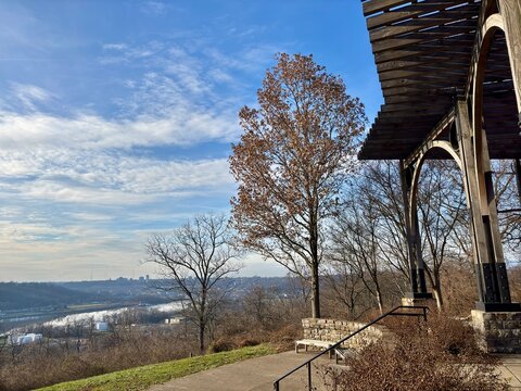 Scenic overlook with wooden pergola, trees, view of river, skyline