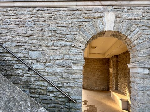 Closeup of a stone archway leading to a shaded interior with a bench