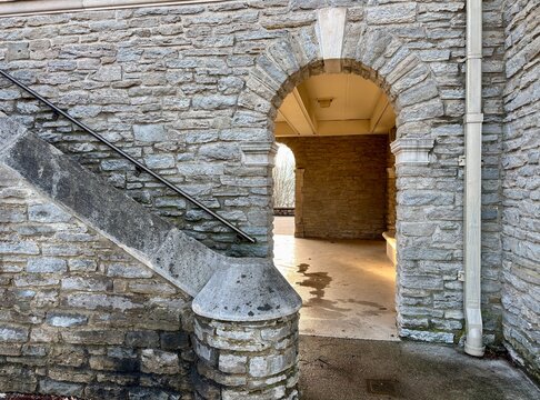 Stone staircase with handrail, arched passageway bathed in soft light