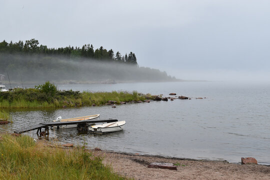 Calm morning at the lake with boats and a misty landscape