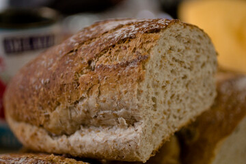 Close-up of artisan multigrain bread loaf with crisp crust, showcased on a rustic wooden board in warm natural light.