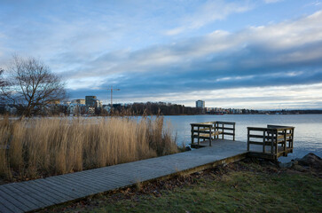 Naklejka premium Dry reeds by a wooden bridge by the lake Malaren (Mälaren) on winter day, View of new residential area of Oster Malarstrand, Vasteras, Sweden, Scandinavia, Europe
