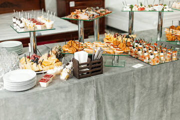a table with snacks and drinks, decorated for a buffet or banquet. There are various dishes on...