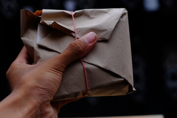 Packaged rice parcel neatly wrapped in brown paper, secured with pink string, nasi lemak wrapper