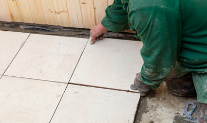 A man is laying down on the ground and working on a tile floor