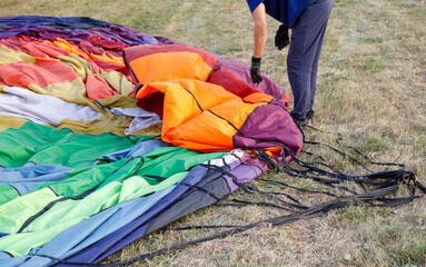 A man is pulling apart a large colorful parachute