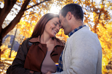 Beautiful young couple hugging in autumn park.
