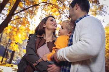 Young family with little son in autumn park on sunny day. Family autumn portrait