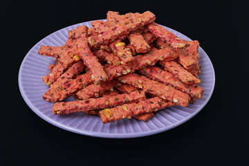 Homemade cookies with vegetable and seed filling on a plate, top view on a black background