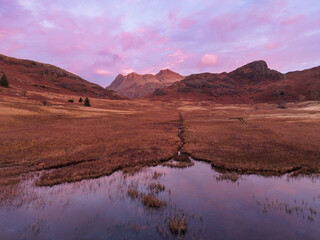 Beautiful aerial drone landscape image of Blea Tarn and Langdale Valley in Lake District during vibrant Autumn sunrise