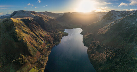 Dramatic aerial drone landscape in Autumn Winter of snowcapped mountains around Buttermere in Lake District at sunrise