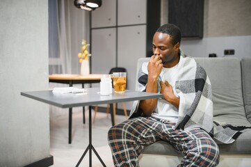 Man using nasal spray for relief from allergies or cold, sitting in a cozy home setting