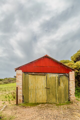 A colorful shed that used to be a chalk factory, but is now abandoned in the historic mining town of Inneston on the Yorke Peninsula in South Australia where it is shown under an overcast sky.