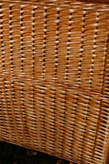part of a wicker basket made of light brown twigs. The basket stands on a wooden surface.