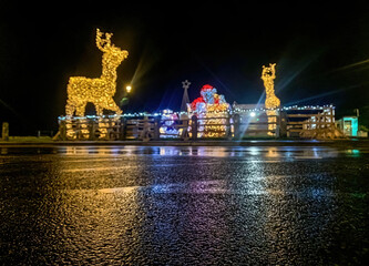 Santa and reindeer light display at night in Salthill, Galway, Ireland, reflected beautifully on the wet road