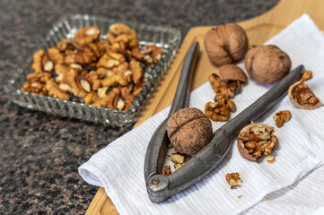 Next to it, on the kitchen countertop, there is a crystal vase with walnut kernels and a wooden cutting board with walnuts and an old aluminum nutcracker.