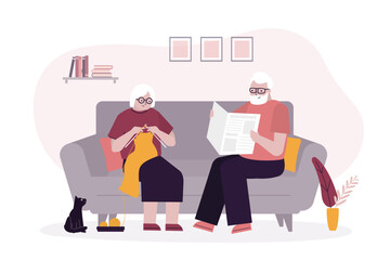 Elderly couple spending a relaxing day enjoying their hobbies sitting in the living room at home knitting and reading. Aged people together, grandparents.