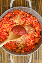 Adding a tomato paste to a pot with chopped vegetables