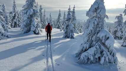 Aerial view of ski touring man crossing winter mountains, fresh snow.