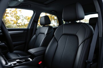 Close-up of modern car interior, focusing on leather seats with stitching, sunlit windows, and natural light, showcasing comfort and design. Ai generative