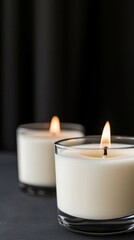 This image depicts beautiful wax candles in glass holders, showcasing a serene and elegant atmosphere with a soft glowing flame against a dark background.