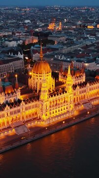 Cinematic shot of Orszaghaz at night. Breathtaking illuminated building of Hungarian parliament on Danube river waterfront. Budapest, Hungary