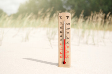 Wooden celsius and fahrenheit scale thermometer in the sand. Ambient temperature plus 14 degrees