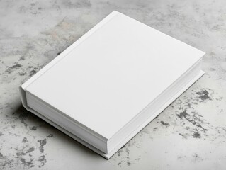 Fototapeta premium A minimalistic hardcover book with a plain white textured cover, resting on a marbled surface, ideal for branding or publishing concepts